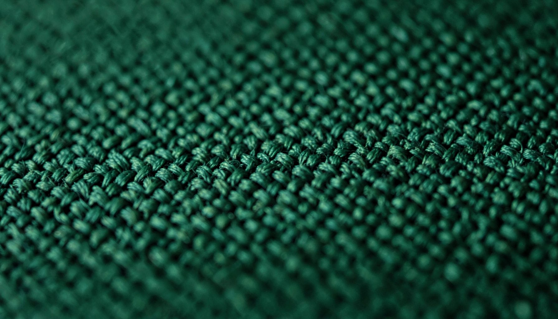 Macro photograph of a dark green woven textile with subtle cross-hatched texture
