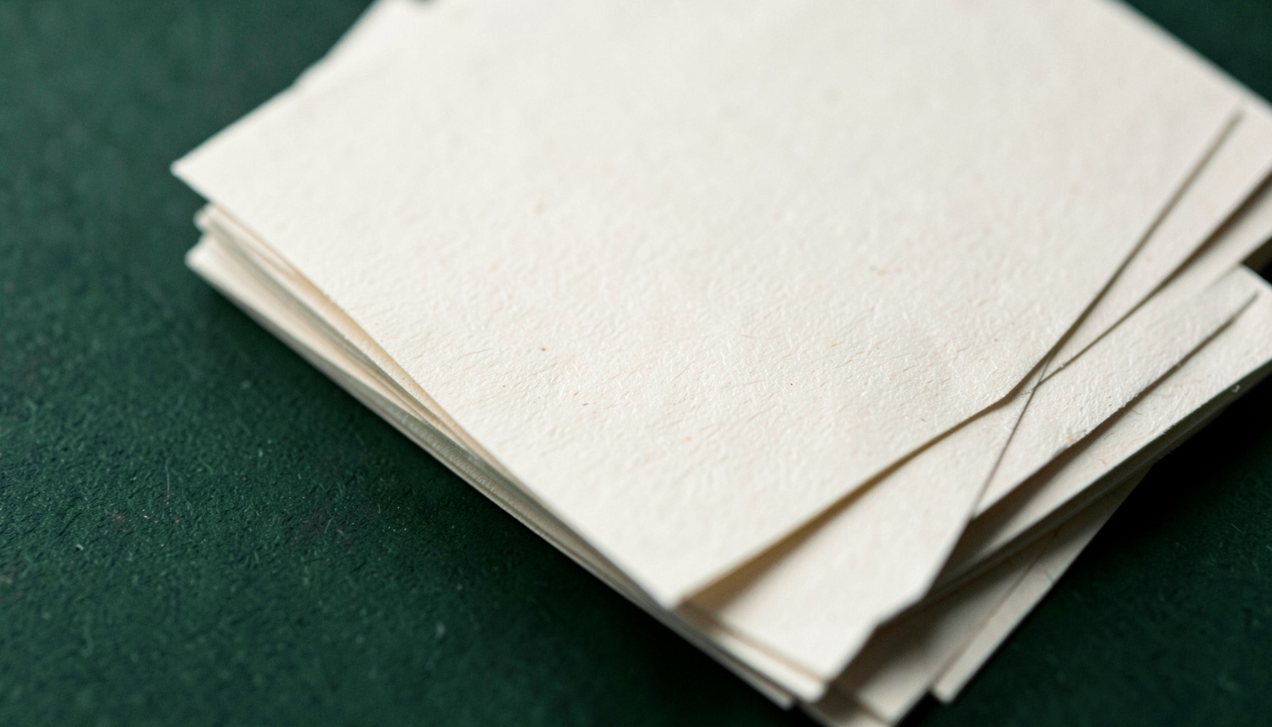 Cream paper documents stacked on a dark green surface, photographed from above